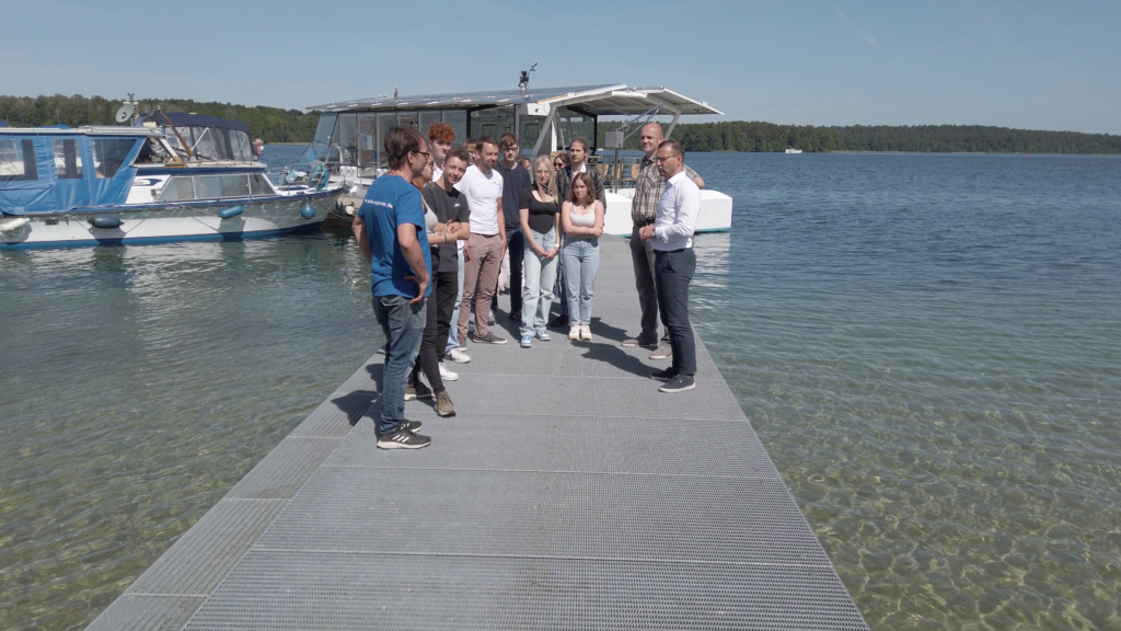 Teilnehmerinnen und Teilnehmer des Symposiums Erneuerbare Energien - die Zukunft unserer Region. Am Werbellin-See, im Hintergrund das Forschungsschiff Solar Explorer